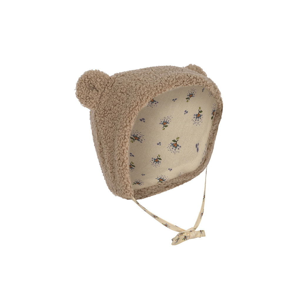 Konges Sløjd Grizz Hat Oxford Tan is een mutsje van teddy stof met oortjes bovenop. Het mutsje bedenkt het hoofdje goed tot in de nek en over de oren en kan worden vast gemaakt met een strikje
