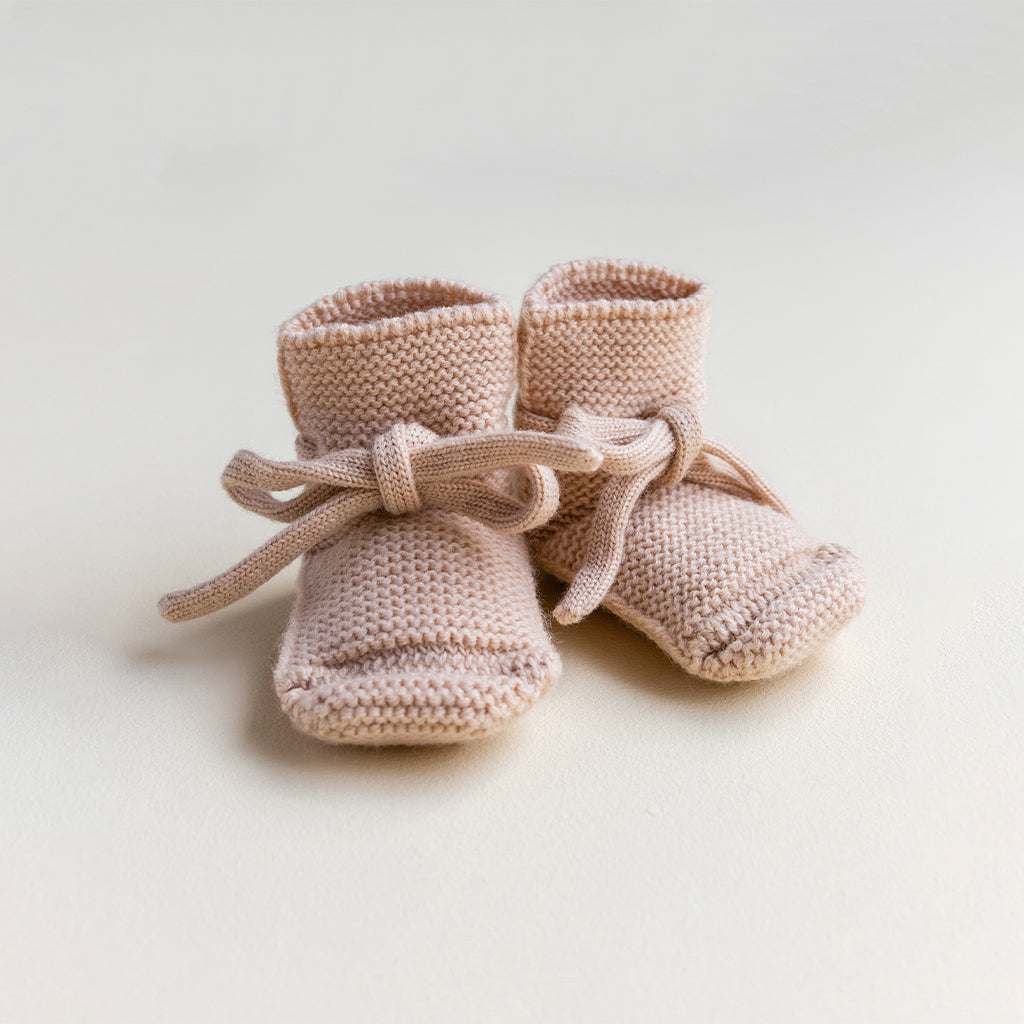 Hvid merinowollen booties in Apricot. Gebreide babyslofjes die niet afzakken met vetertjes in zachtroze